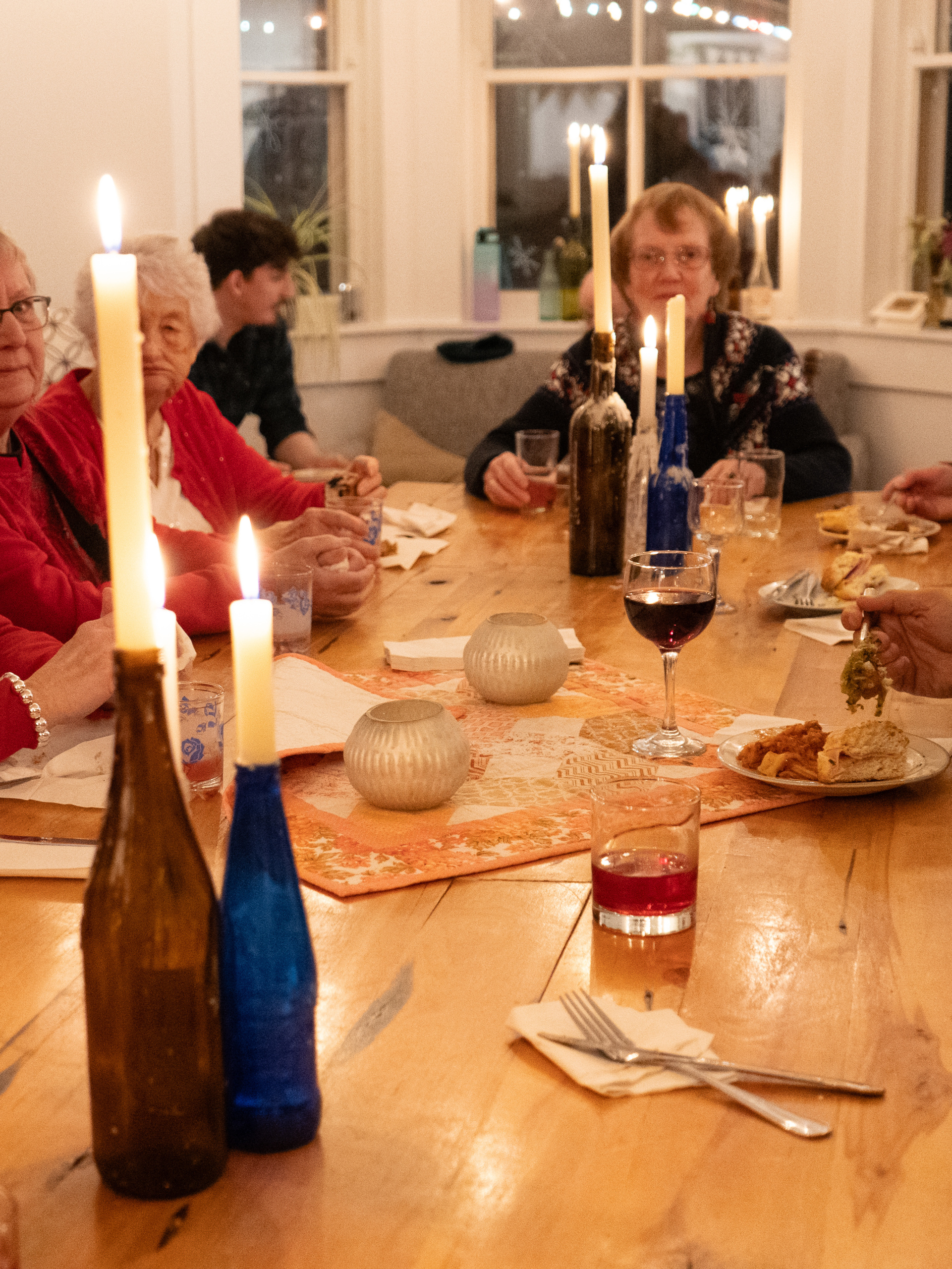 A candlelit dinner gathering with drinks and food, looking at the head of the table