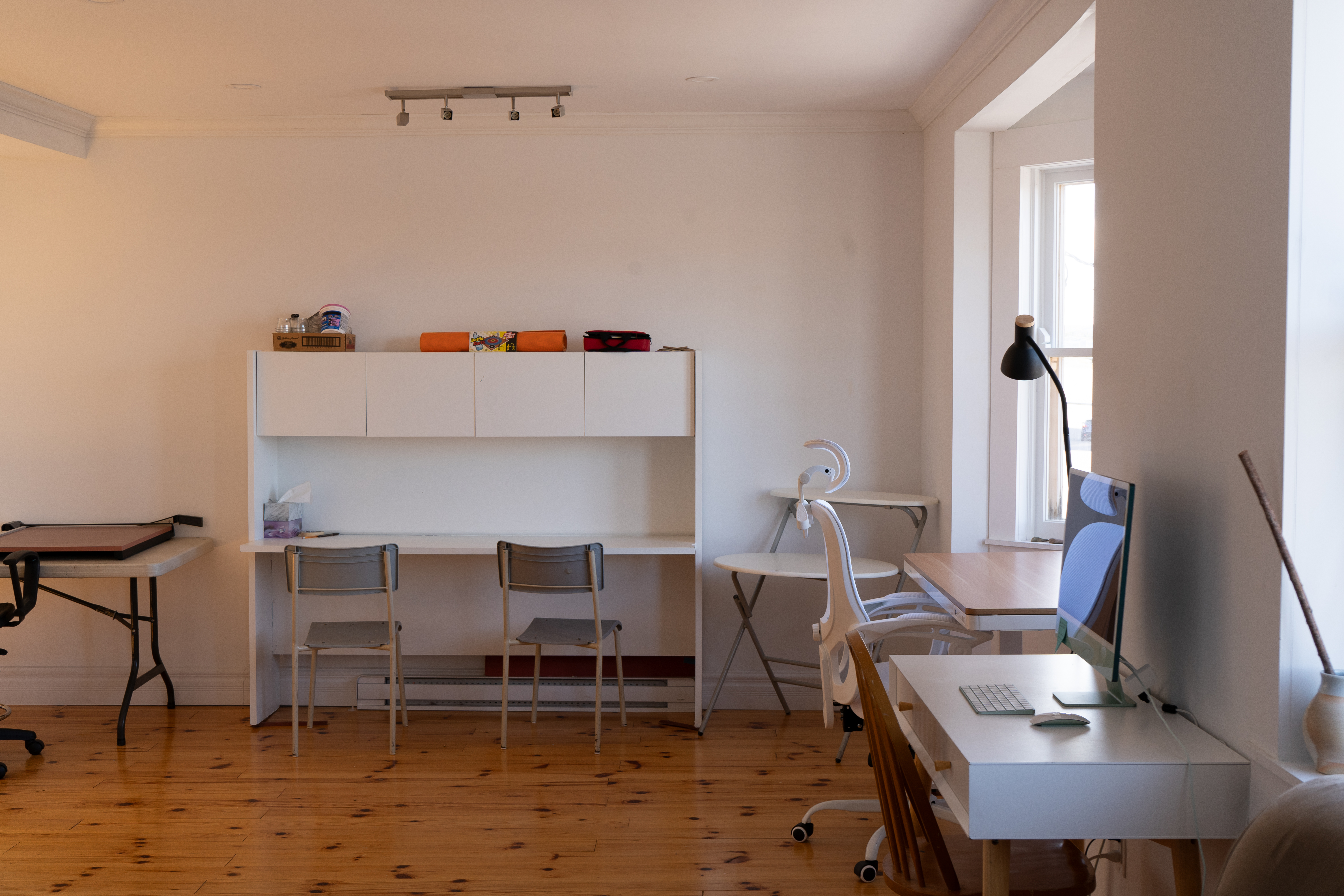Multiple desks and tables for working: a folding table, a desk with cabinet, a standing desk with an office chair and a computer desk with iMac.
