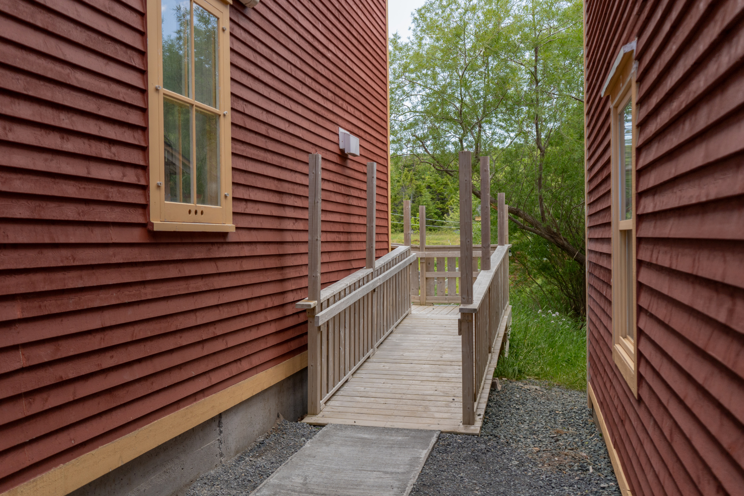 A wooden wheelchair ramp with  handrails shown at an angle, with a left turn leading to the backyard patio.